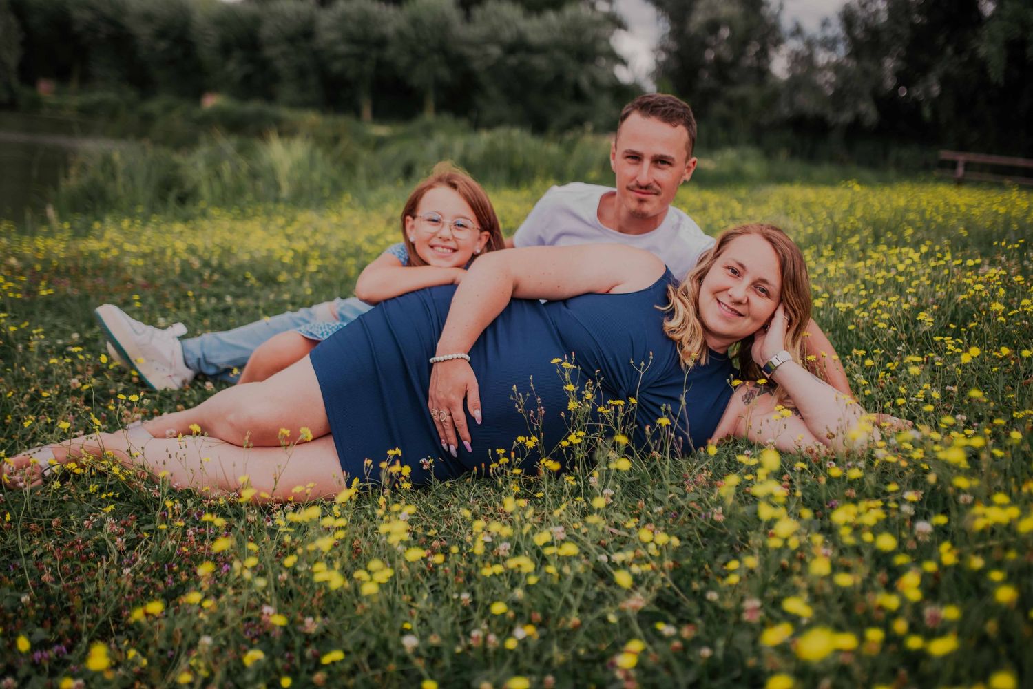 Couple lying together in a field of yellow wildflowers during golden hour.