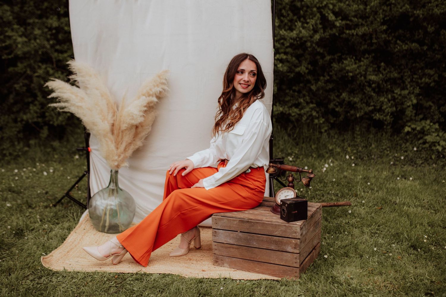 Boho-style outdoor photo session with white fabric backdrop and orange accents.