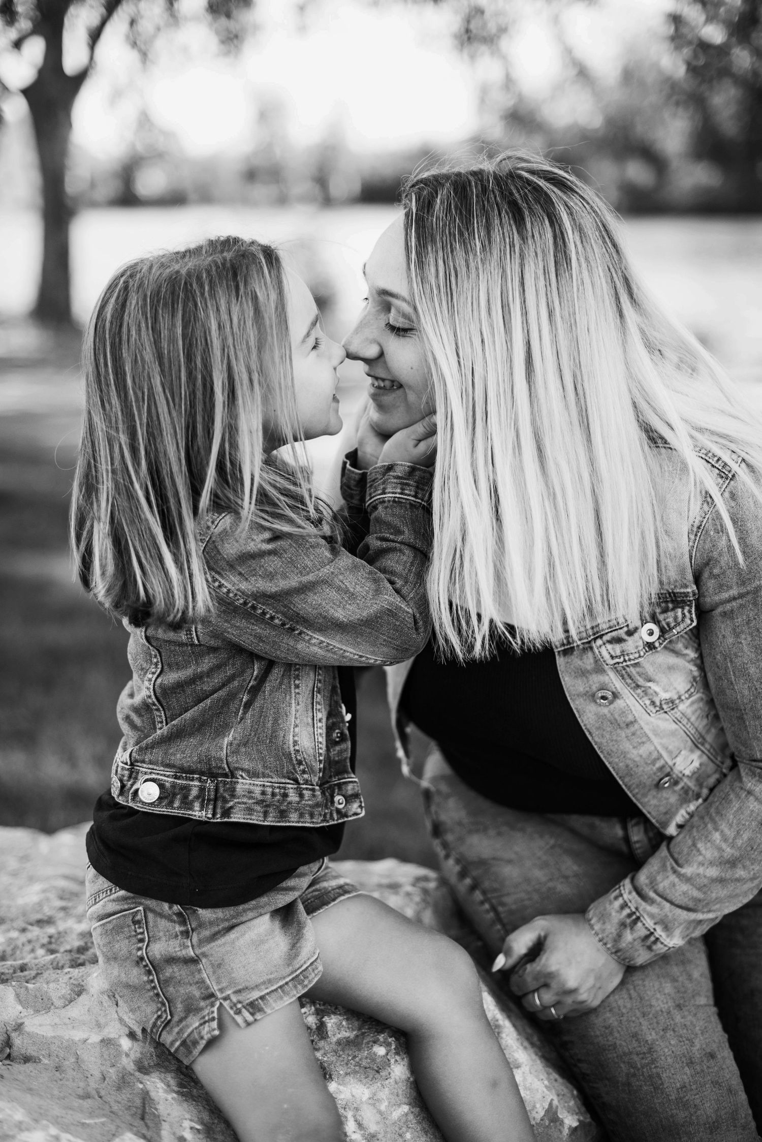Couple in denim sharing playful moments outdoors in black and white photography.