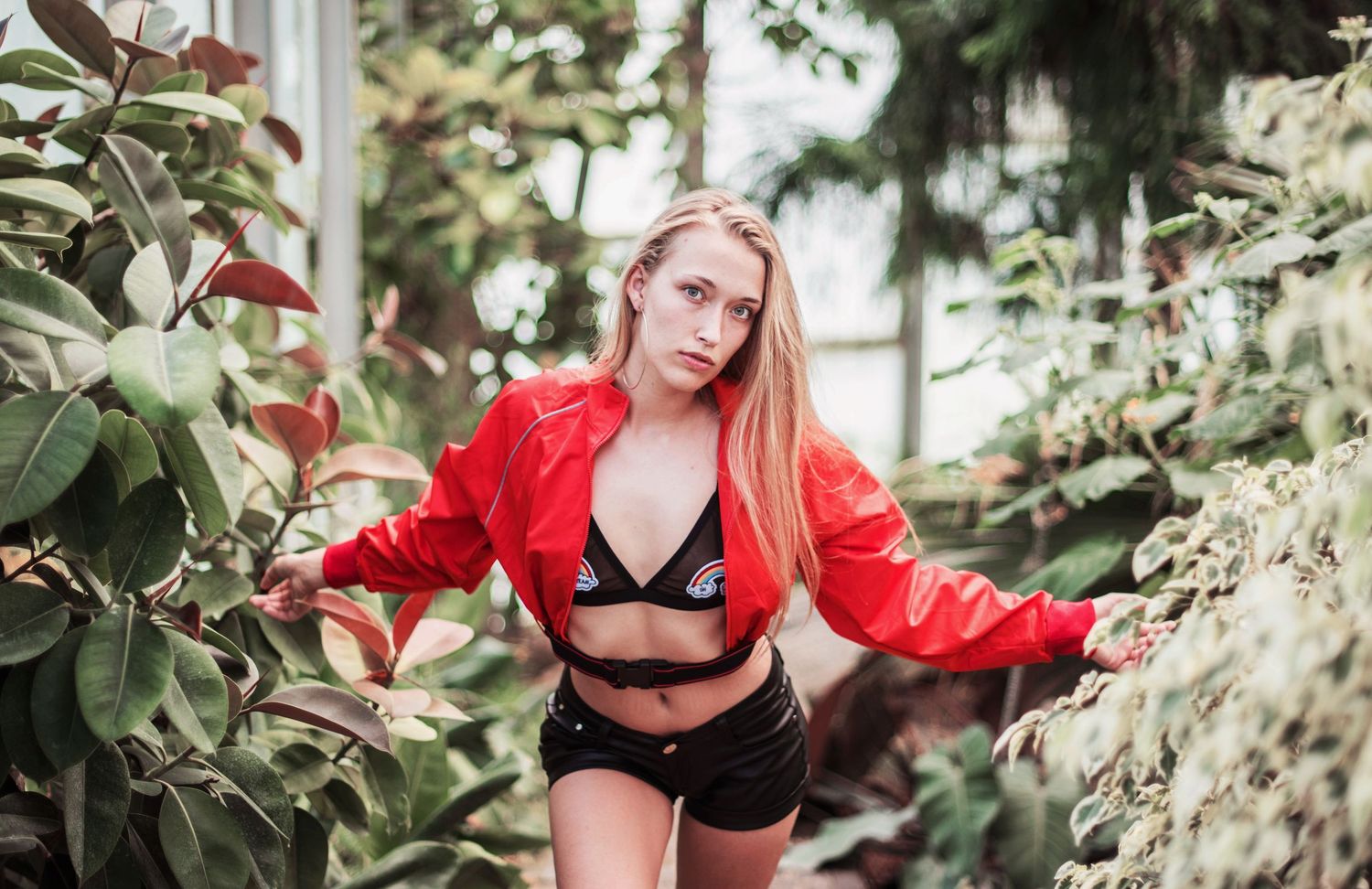 Outdoor fashion photography session in a lush garden setting with red accents.