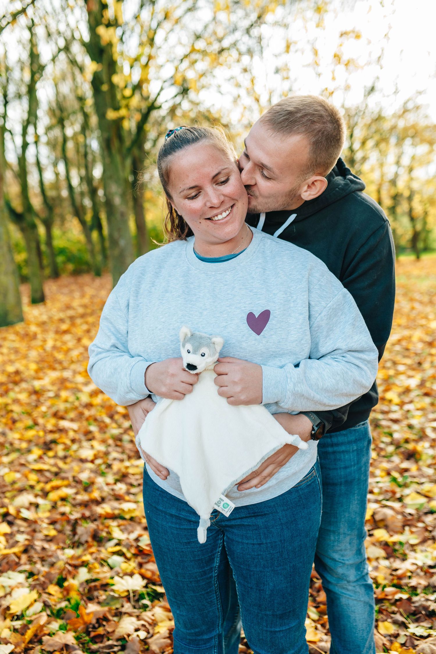 Couple sharing tender moments in a fall setting with colorful autumn leaves on the ground.