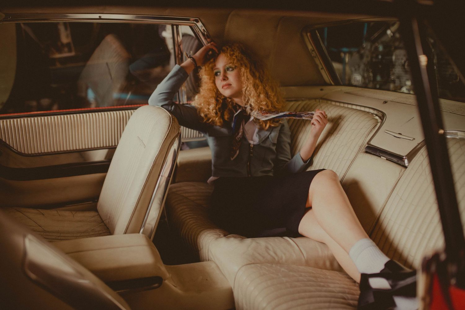 Interior view of a classic car with cream leather seats in warm tones.