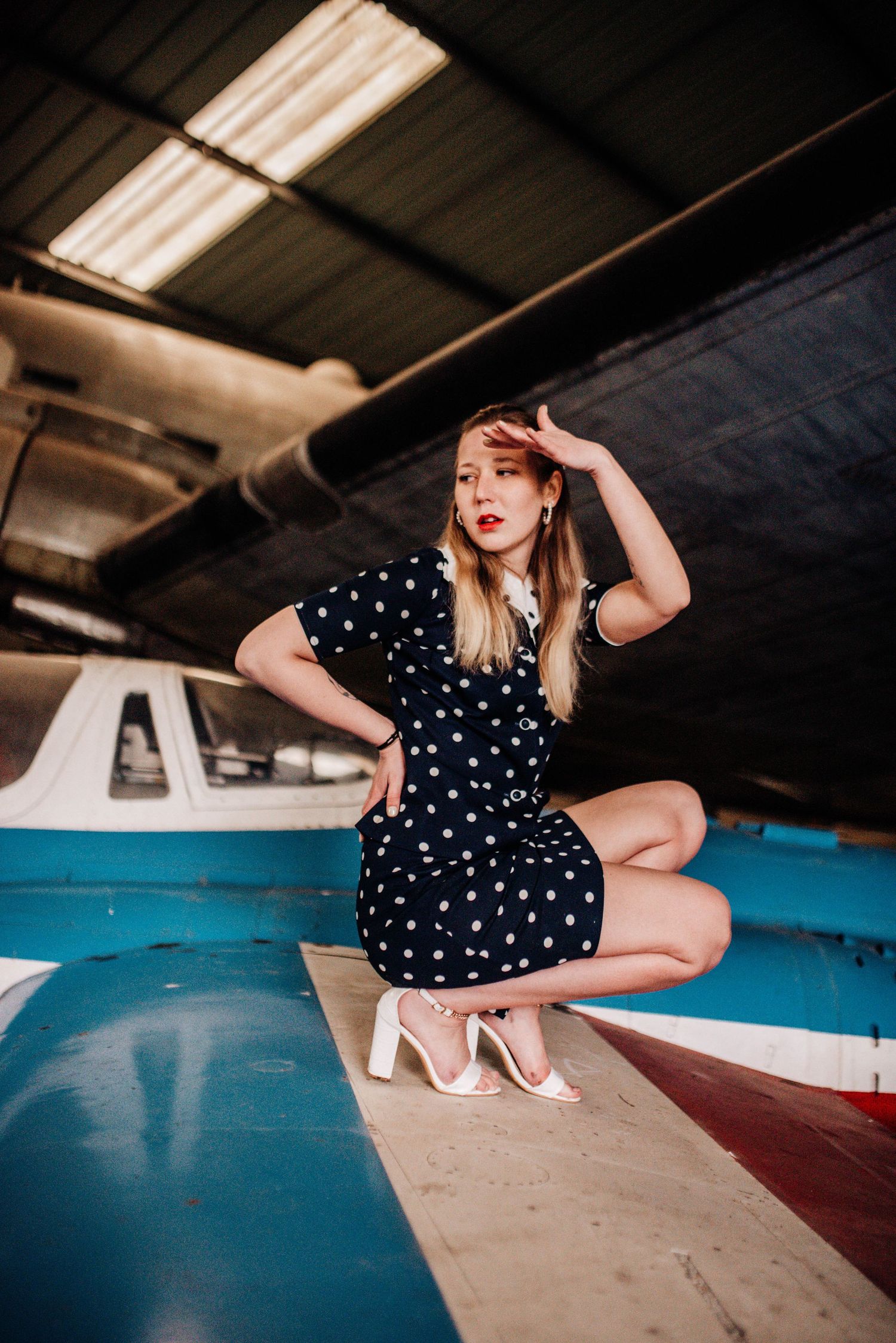 Fashion photography session with vintage aircraft in an indoor hangar setting.