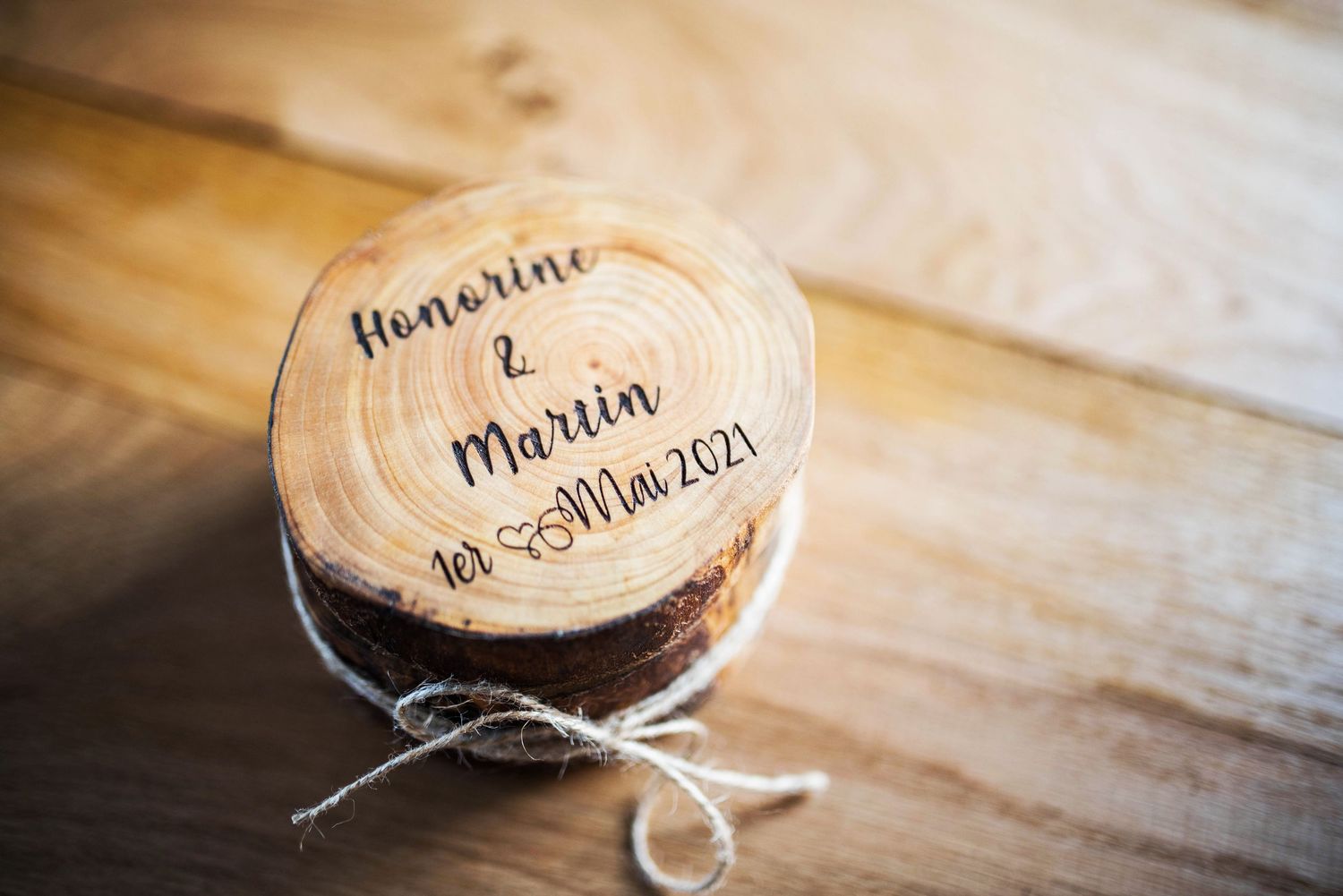 Wooden wedding ring holder with names and date engraved on rustic wood slices.