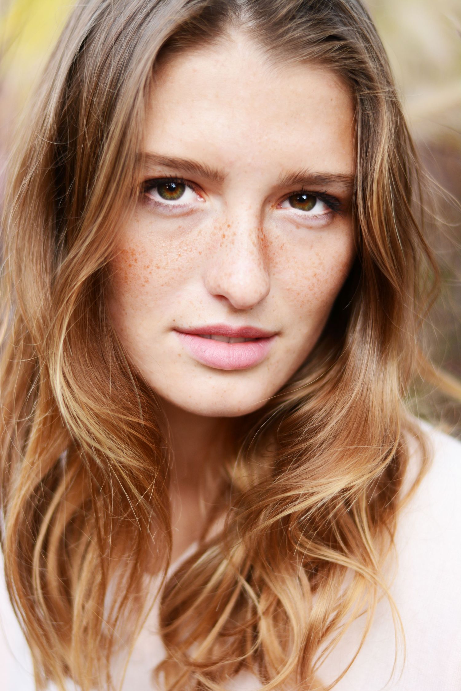 Close-up beauty portrait showing natural freckles and honey-blonde hair.