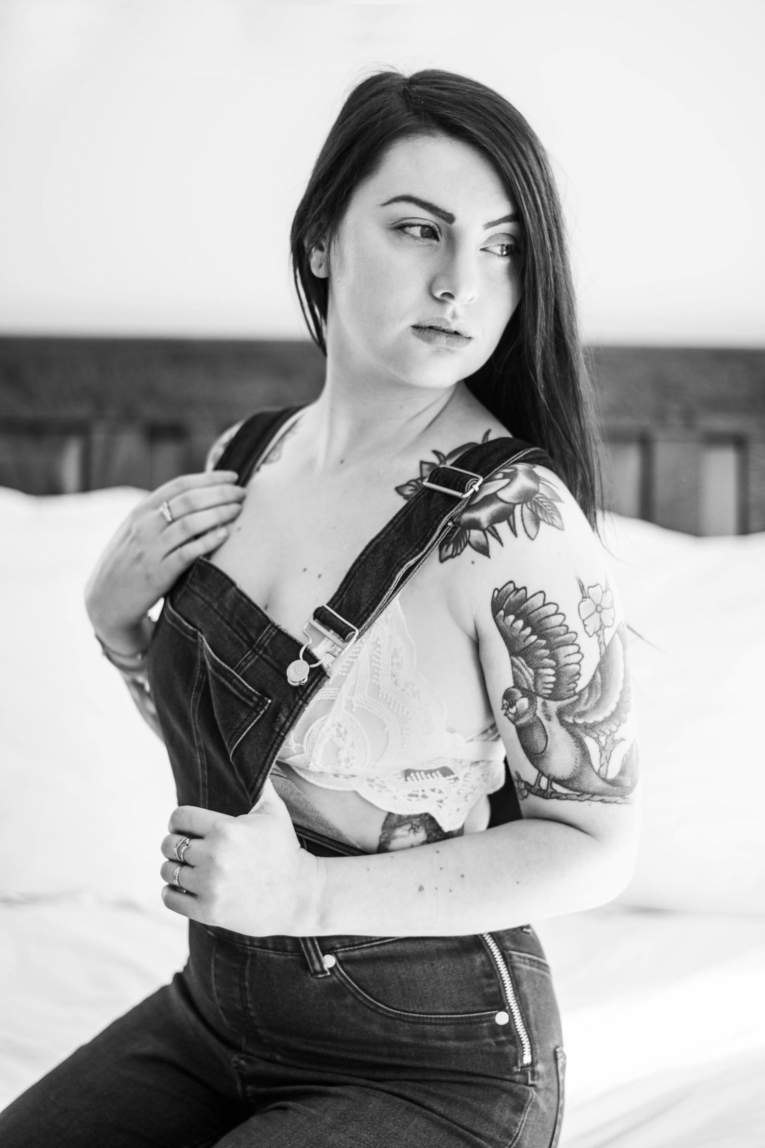 Black and white portrait showing tattoo art and denim overalls in minimalist style.