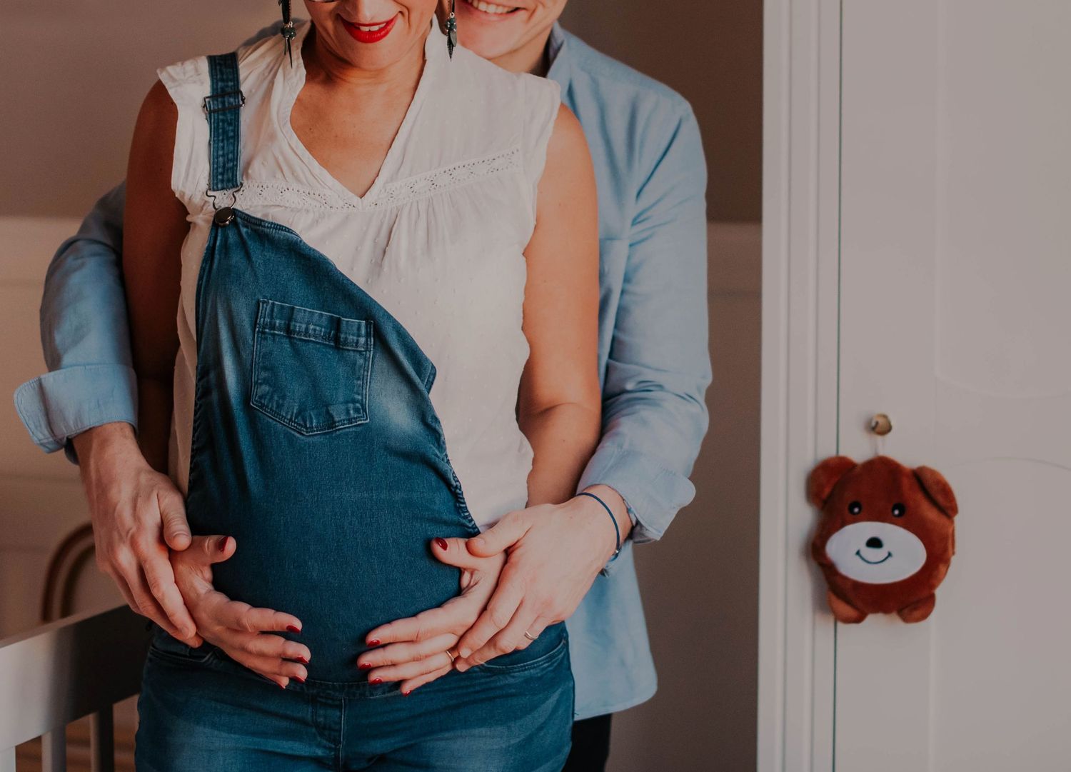 A series of pregnancy announcement photos showing a growing baby bump in denim overalls.