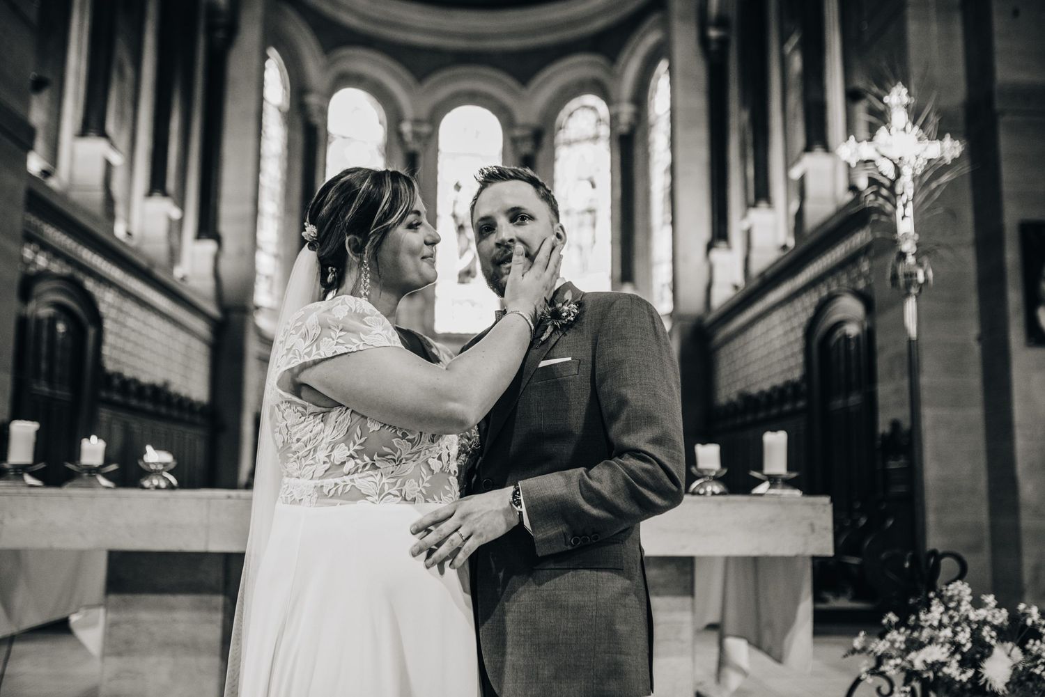Black and white wedding portrait in a church with dramatic arched windows and natural light.