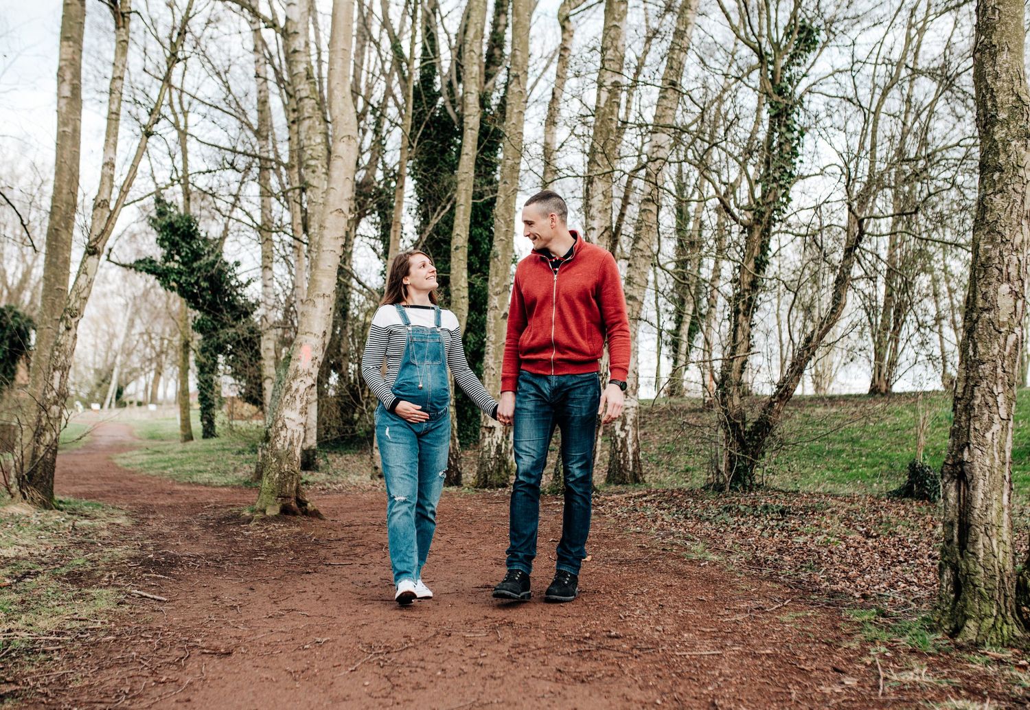 Walking path through a wooded area with bare trees and natural lighting.