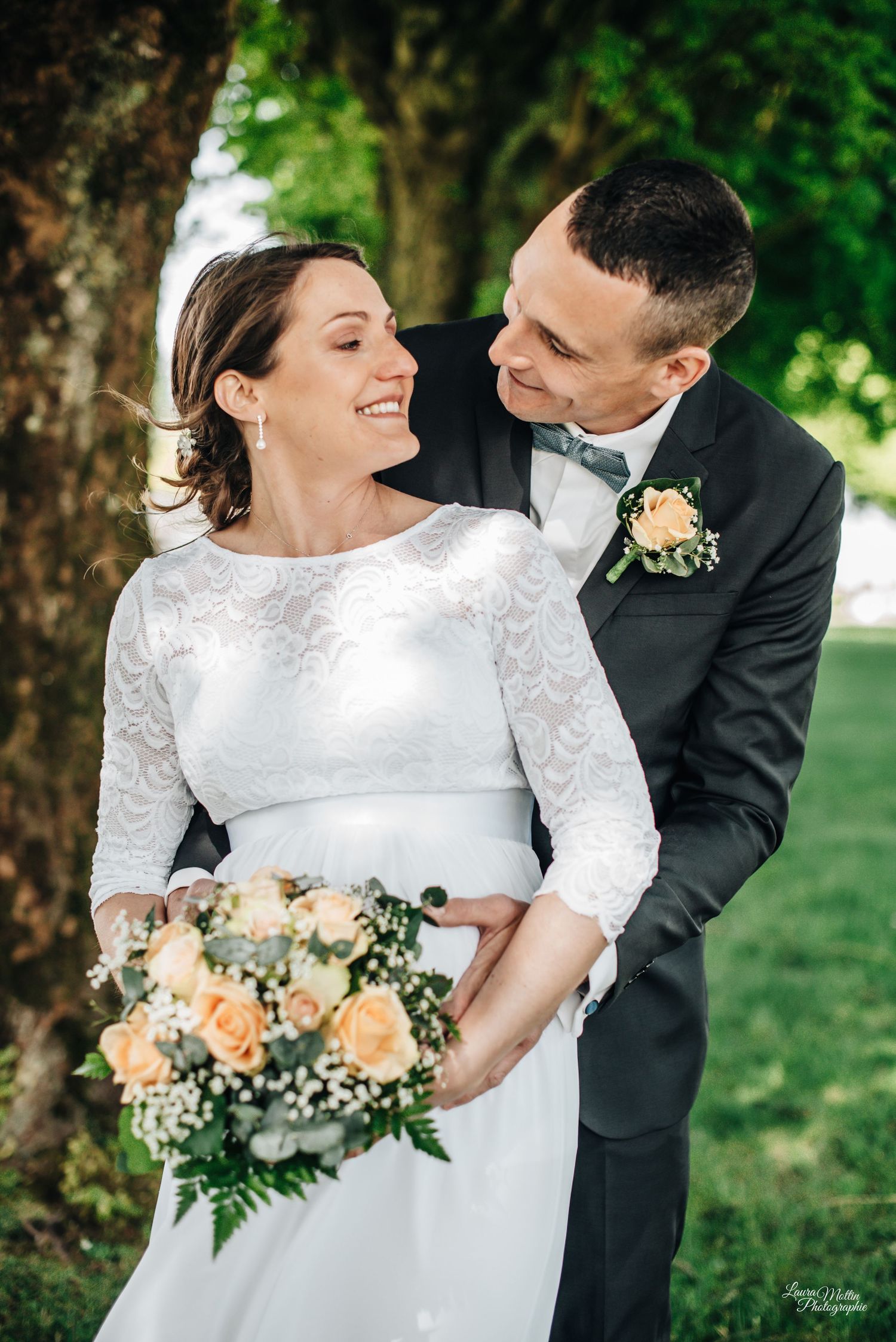 Wedding couple poses with floral bouquet in outdoor garden setting.