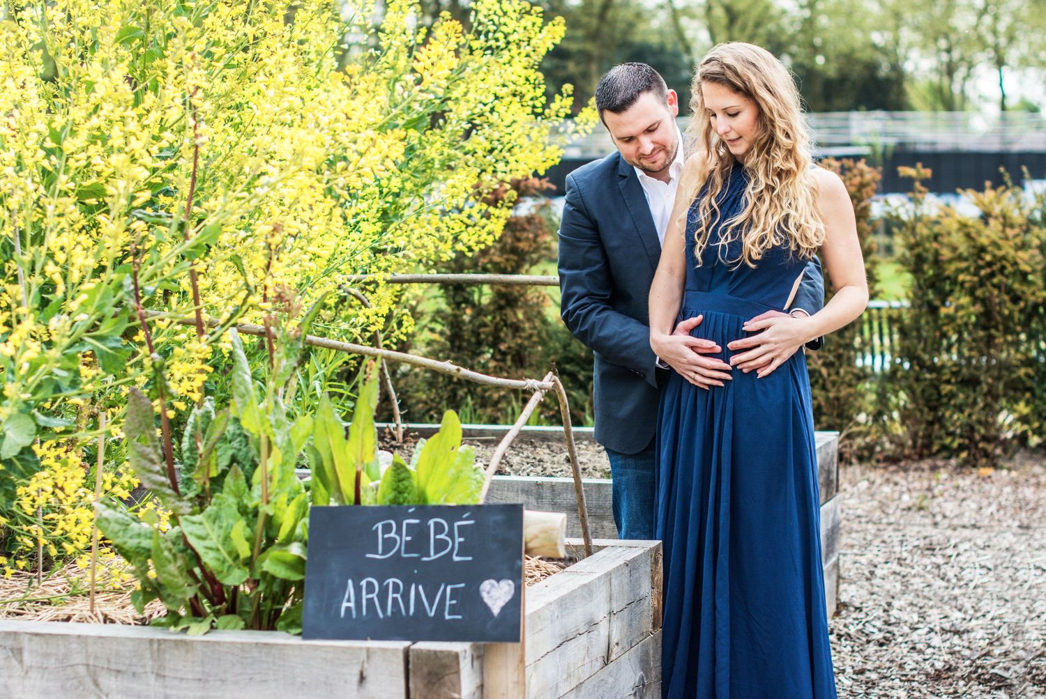 Engagement photos in a garden setting with yellow forsythia bushes and blue attire.
