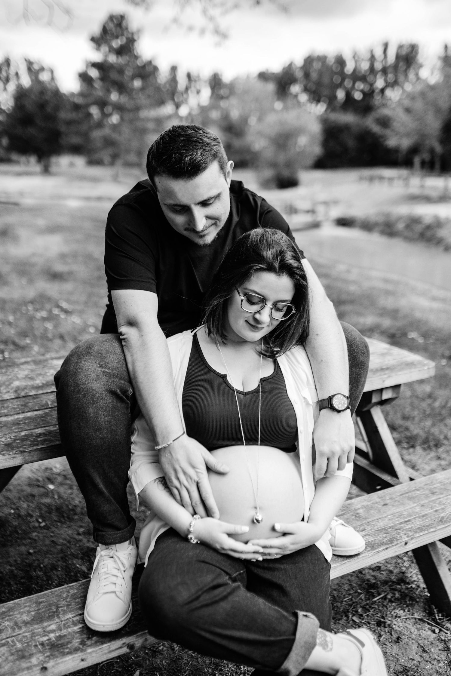 Intimate black and white photo of a couple sharing a tender moment on a wooden bench.