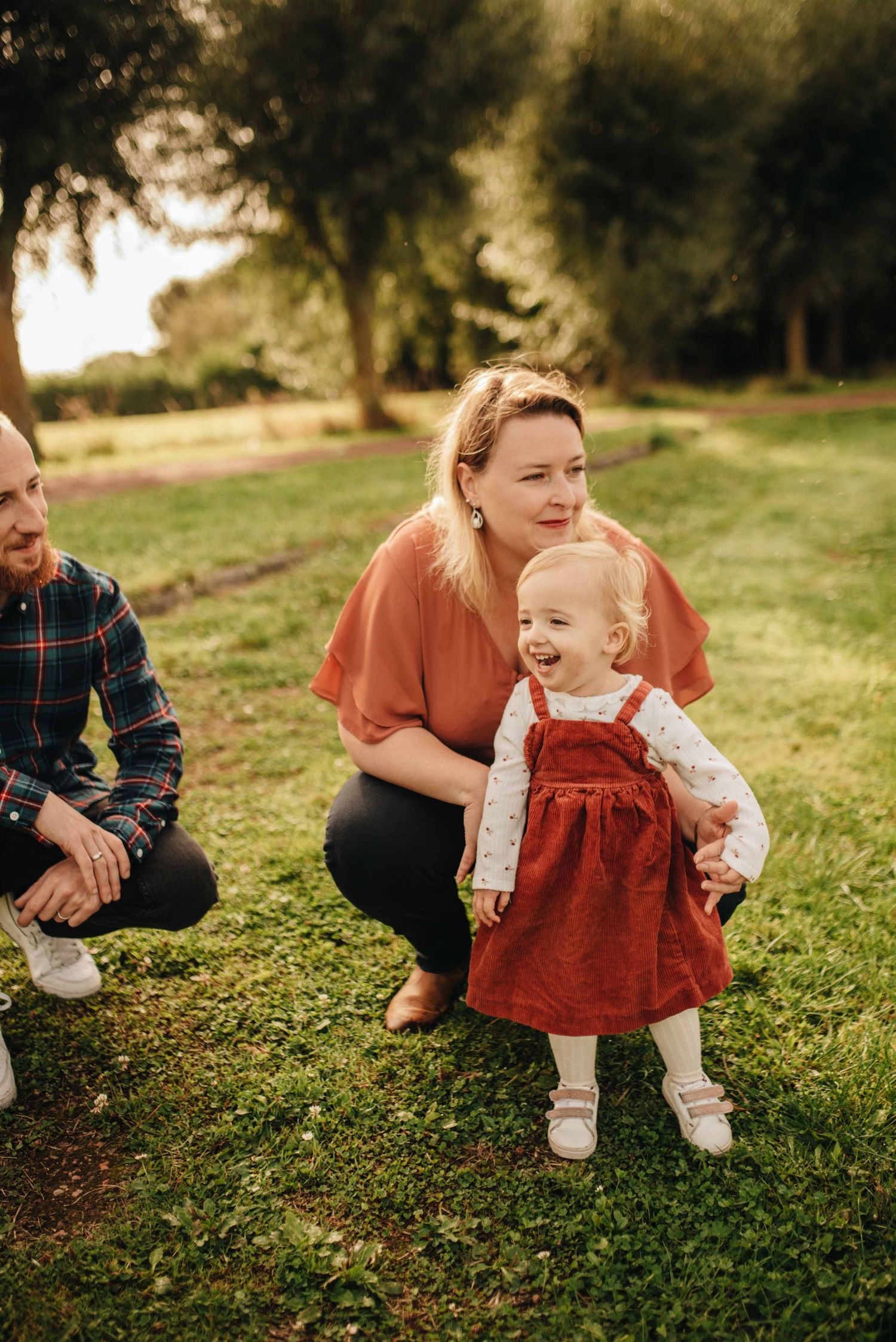 Candid outdoor family moment on grassy lawn during golden hour.