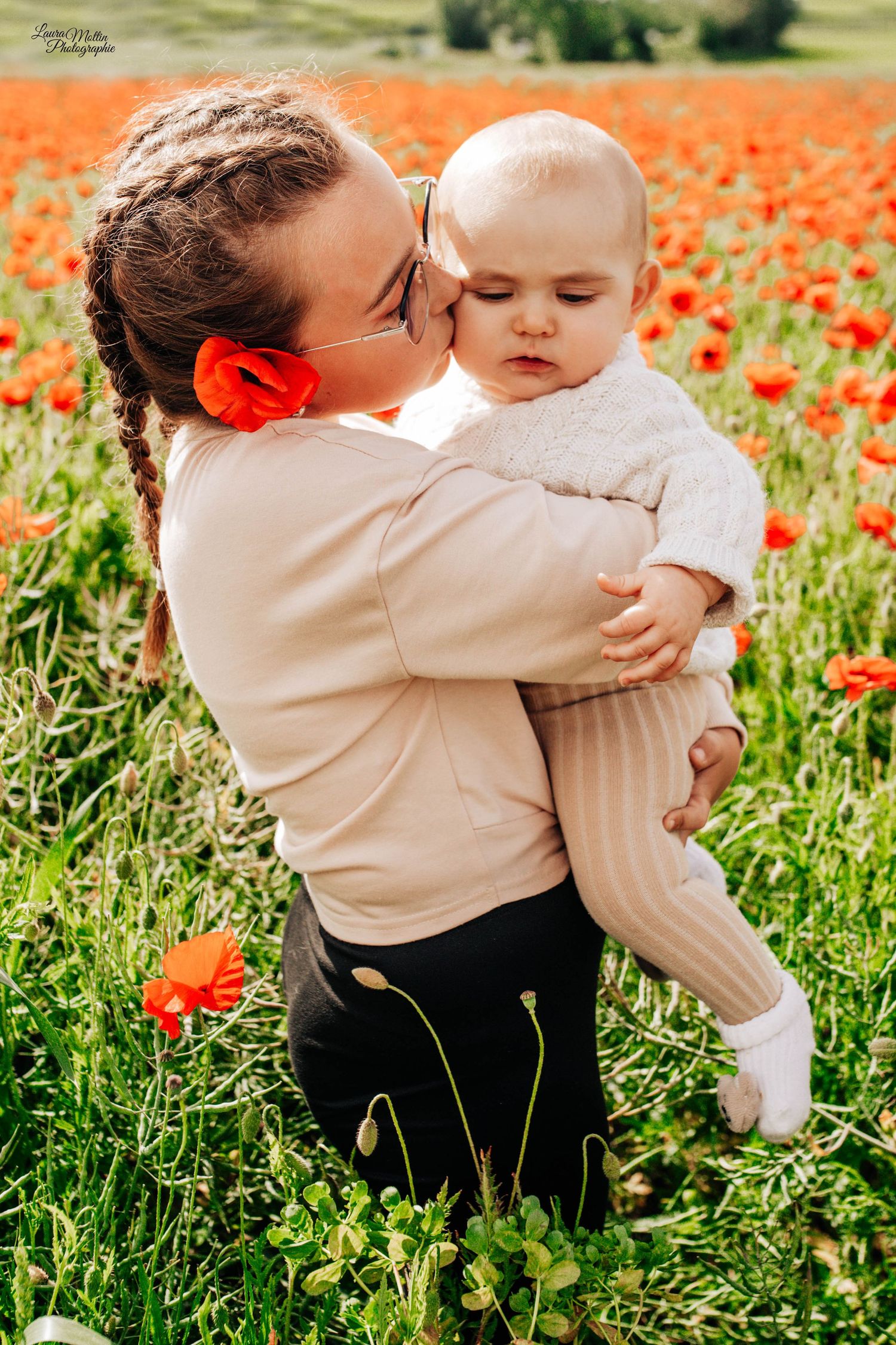 Parent and child sharing tender moments in a vibrant field of red poppies.