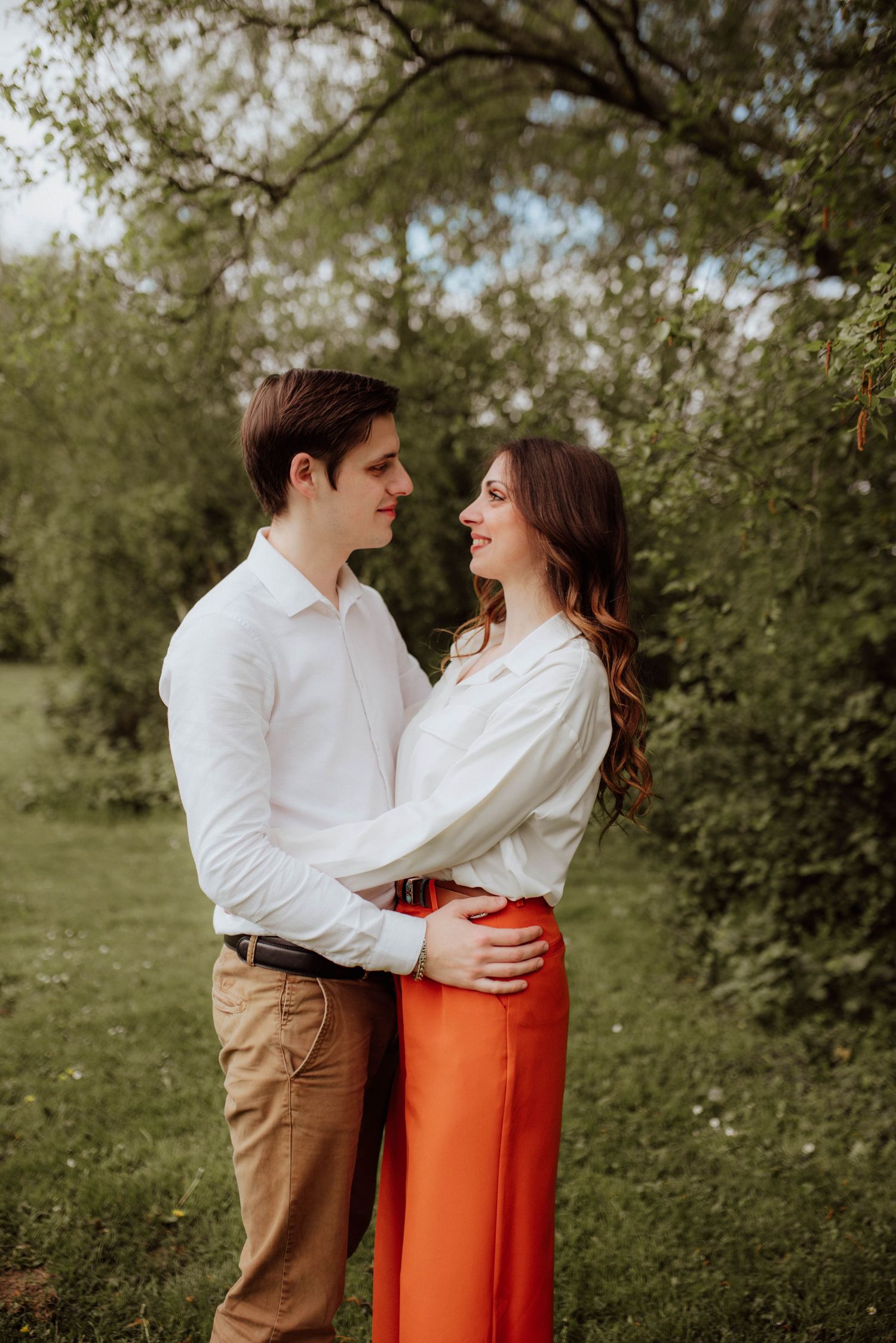 Romantic couple's portrait session with white shirt and orange skirt in a natural outdoor setting.