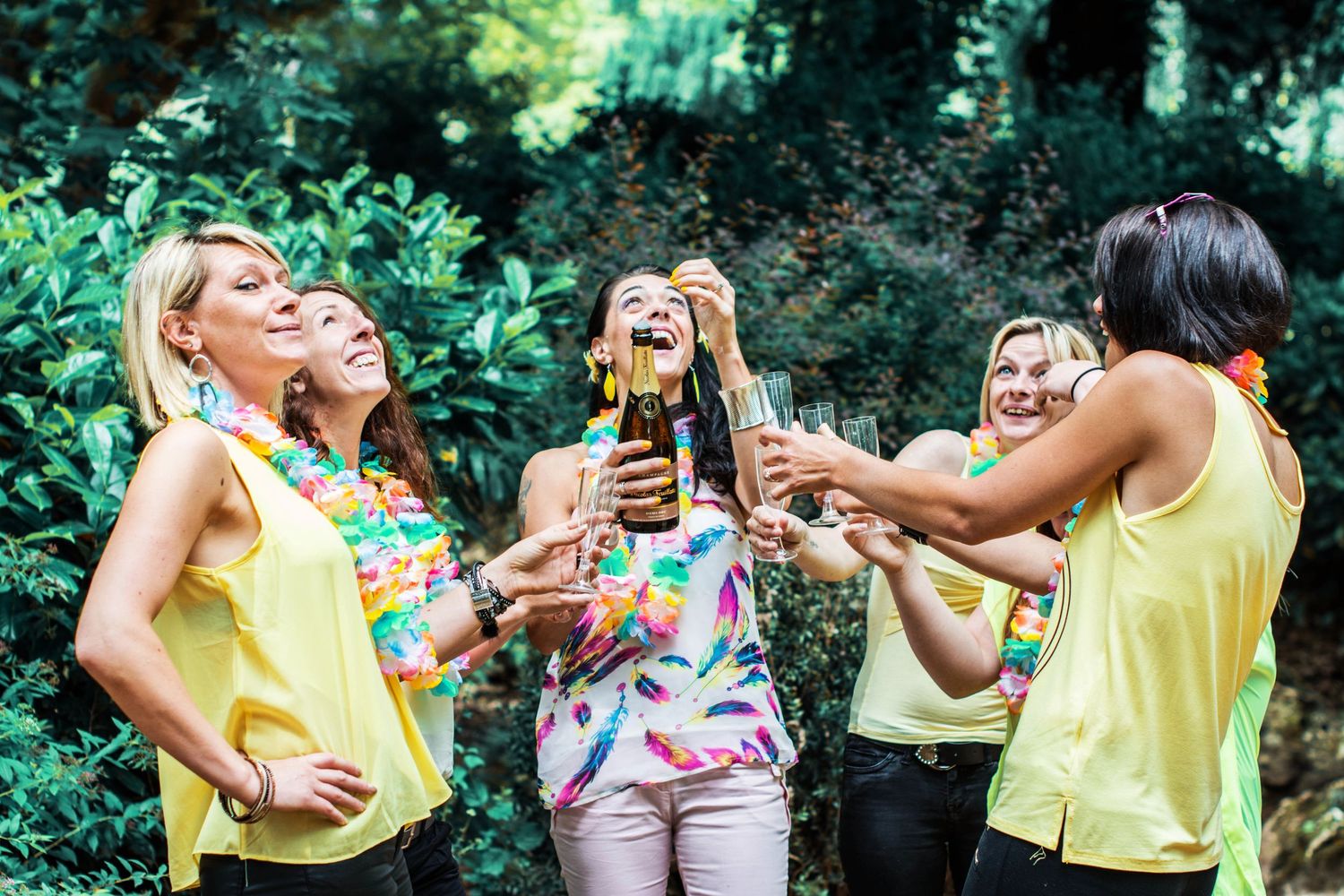 Friends laughing and celebrating in a garden setting with bright summer attire.
