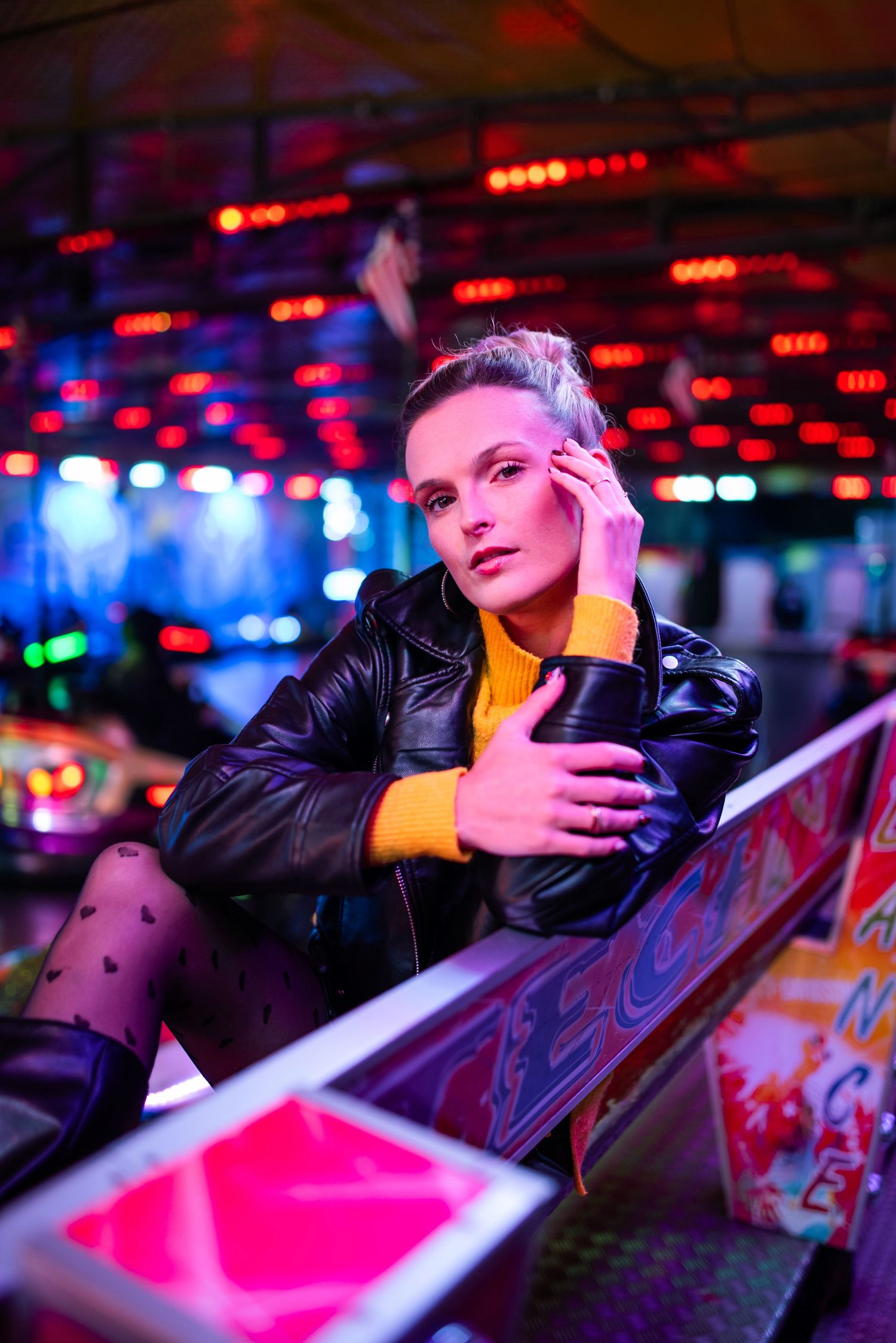 Dramatic portrait with red and blue lighting at an arcade or carnival setting.