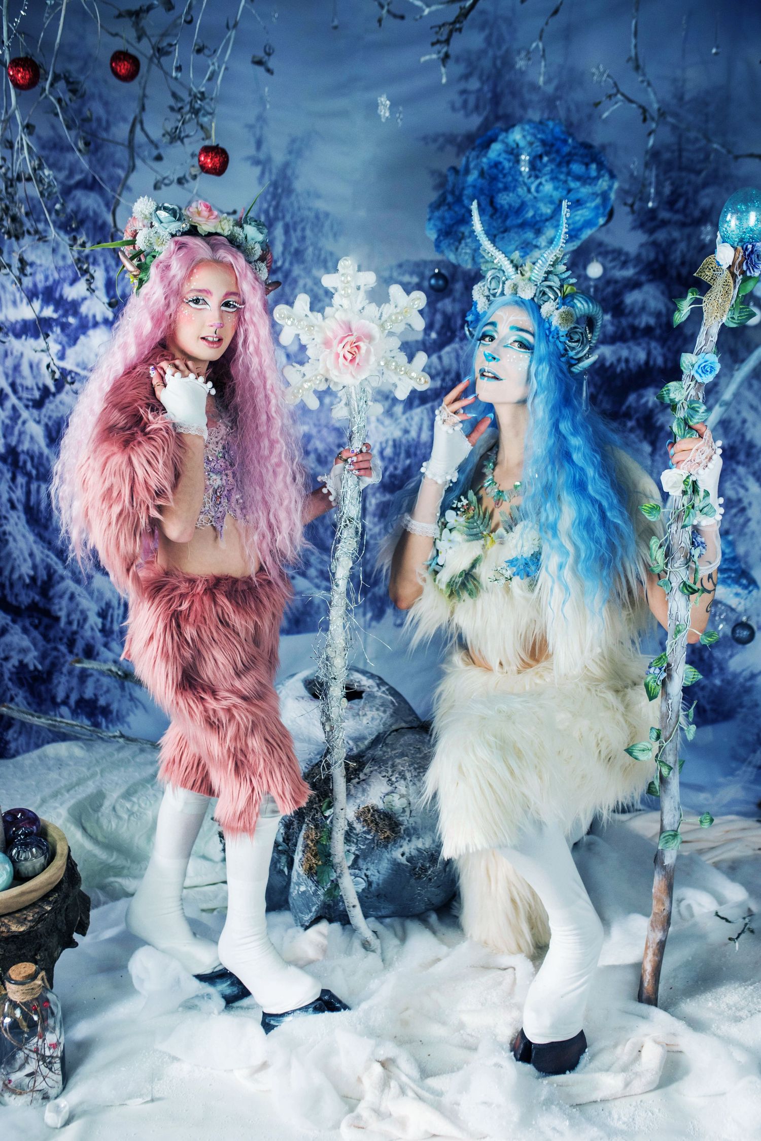 Two figures in fantasy costumes pose in a magical winter wonderland setting with blue lighting and snow.