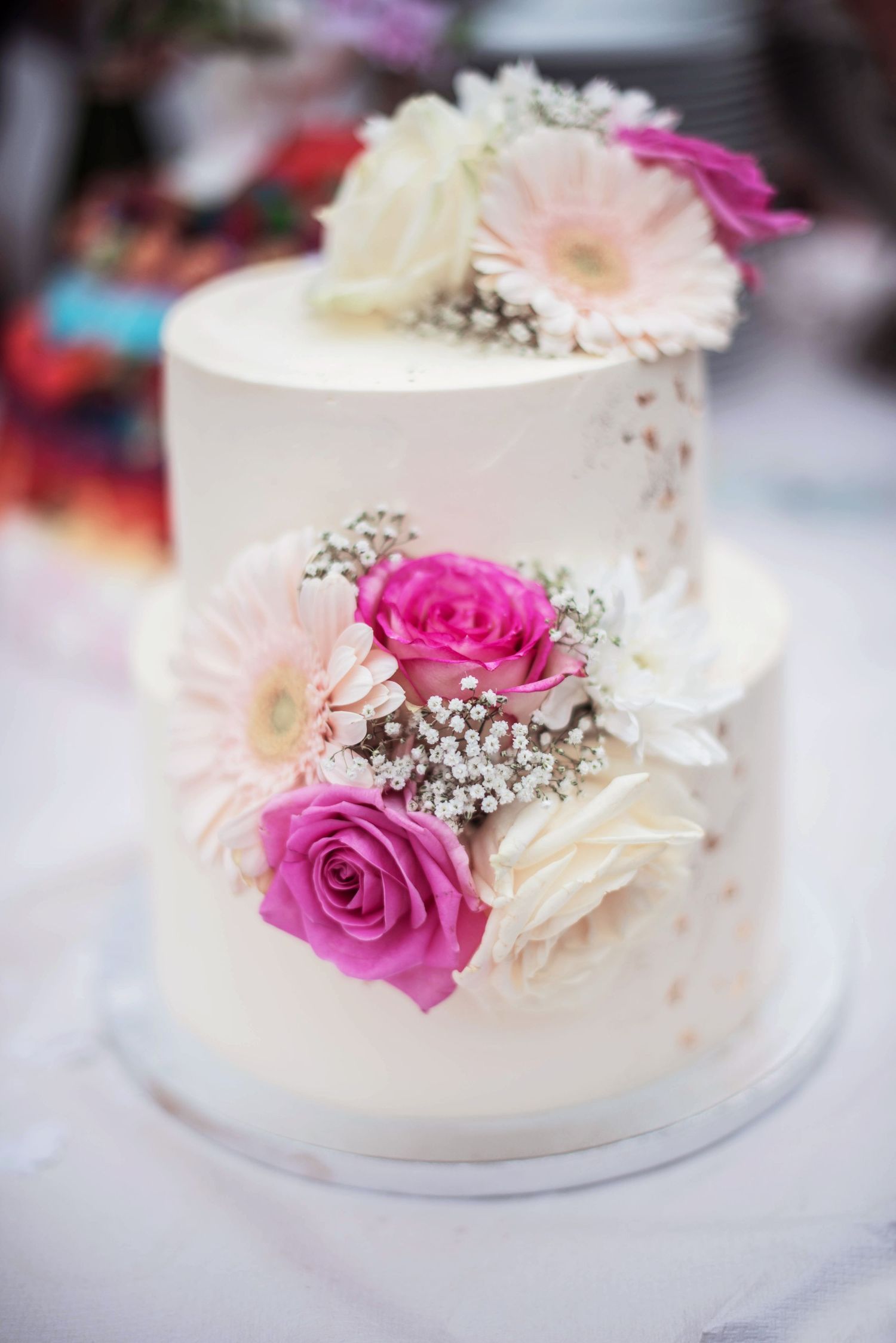 White wedding cake decorated with fresh pink roses and delicate baby's breath flowers.