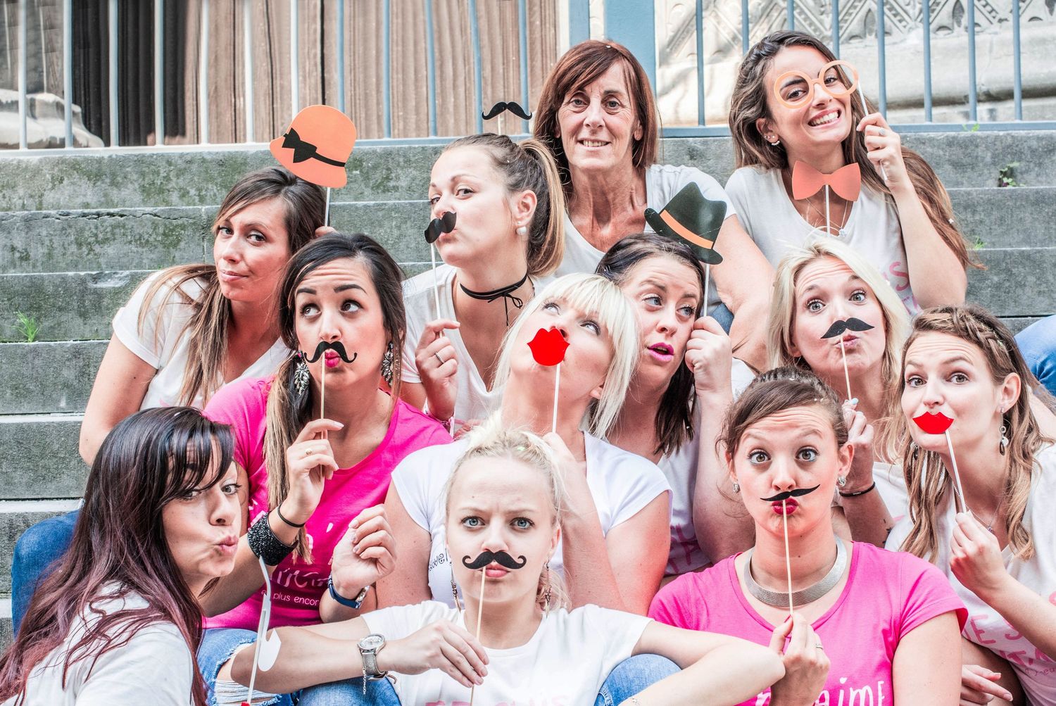 Group wearing matching outfits making silly faces while holding party props outdoors.