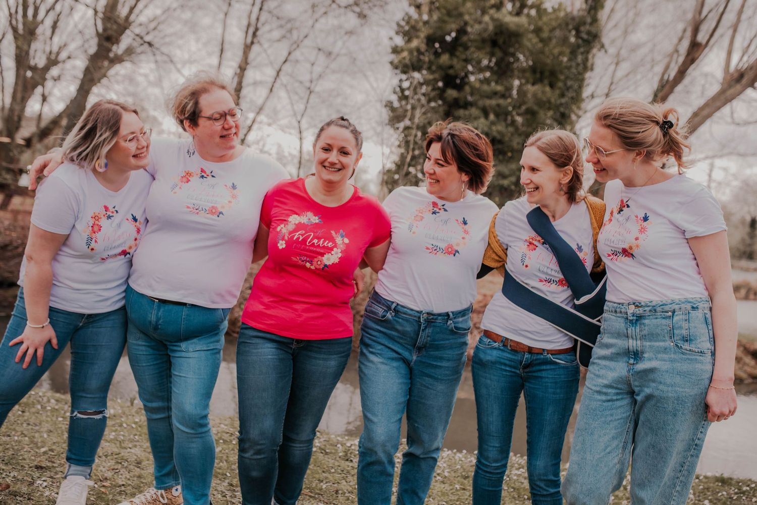 Friends lined up wearing matching jeans and tops for a casual outdoor photo.