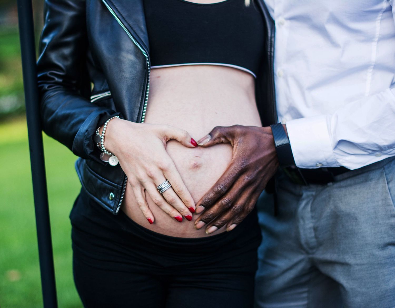 Close-up maternity photos showing hands cradling baby bump against formal attire.