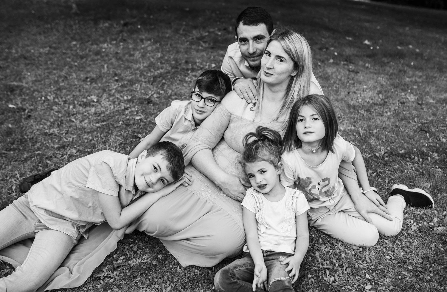 Black and white family moments captured on grass showing playful interactions.