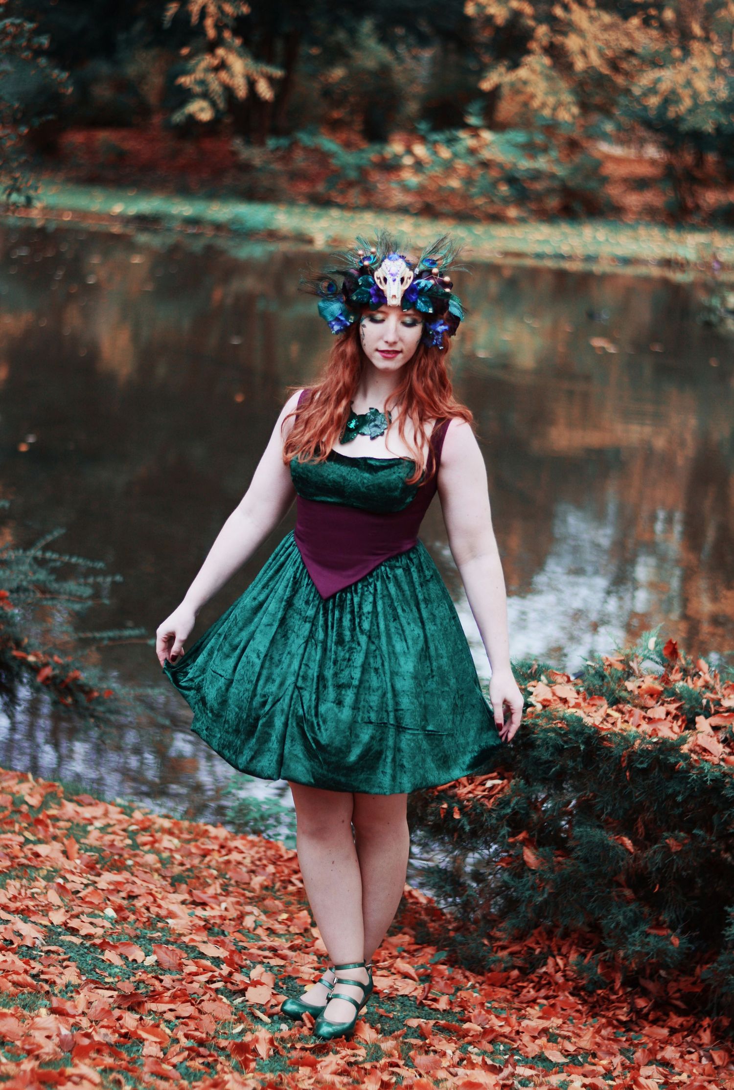 Whimsical forest photoshoot in emerald dress surrounded by autumn leaves.