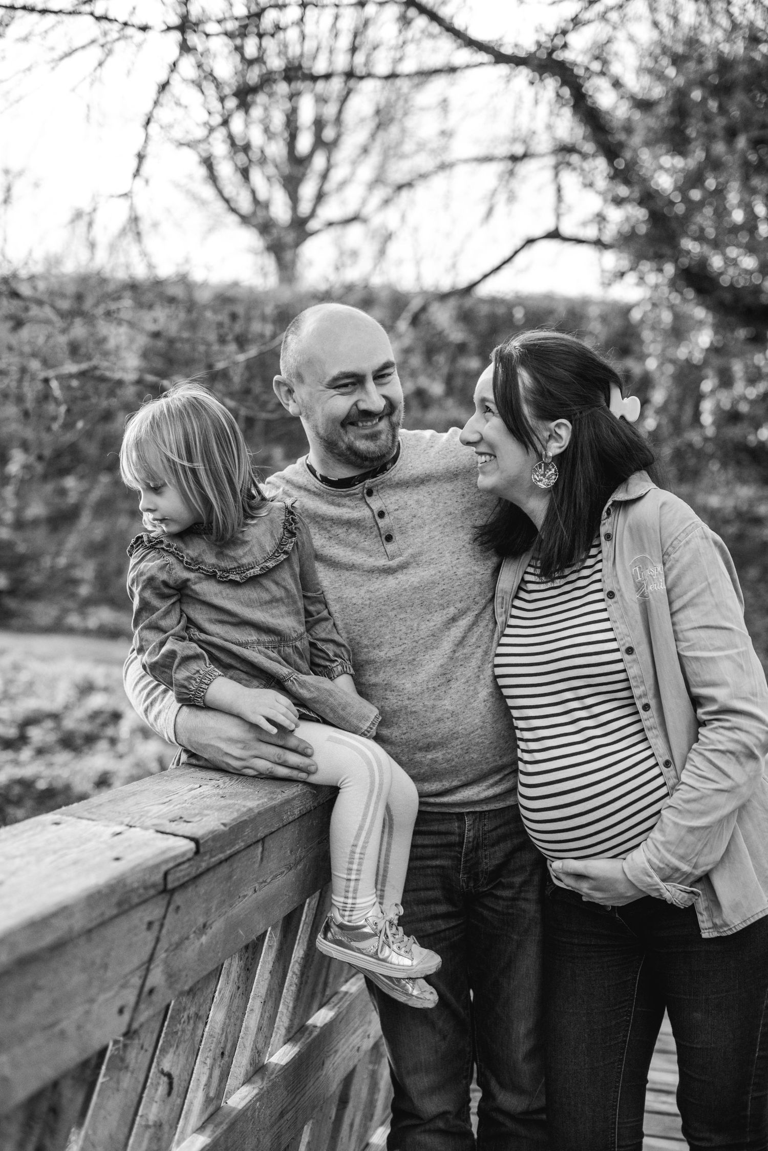 Black and white family portrait captured along rustic wooden railing.