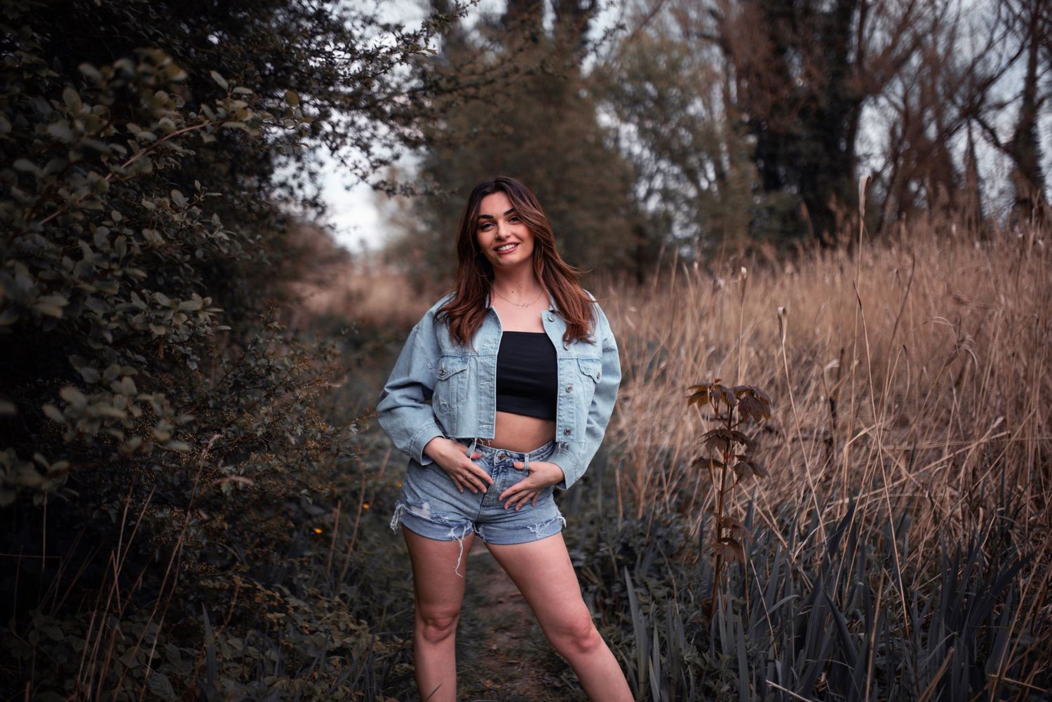Natural outdoor photography session in tall grass and autumn foliage.