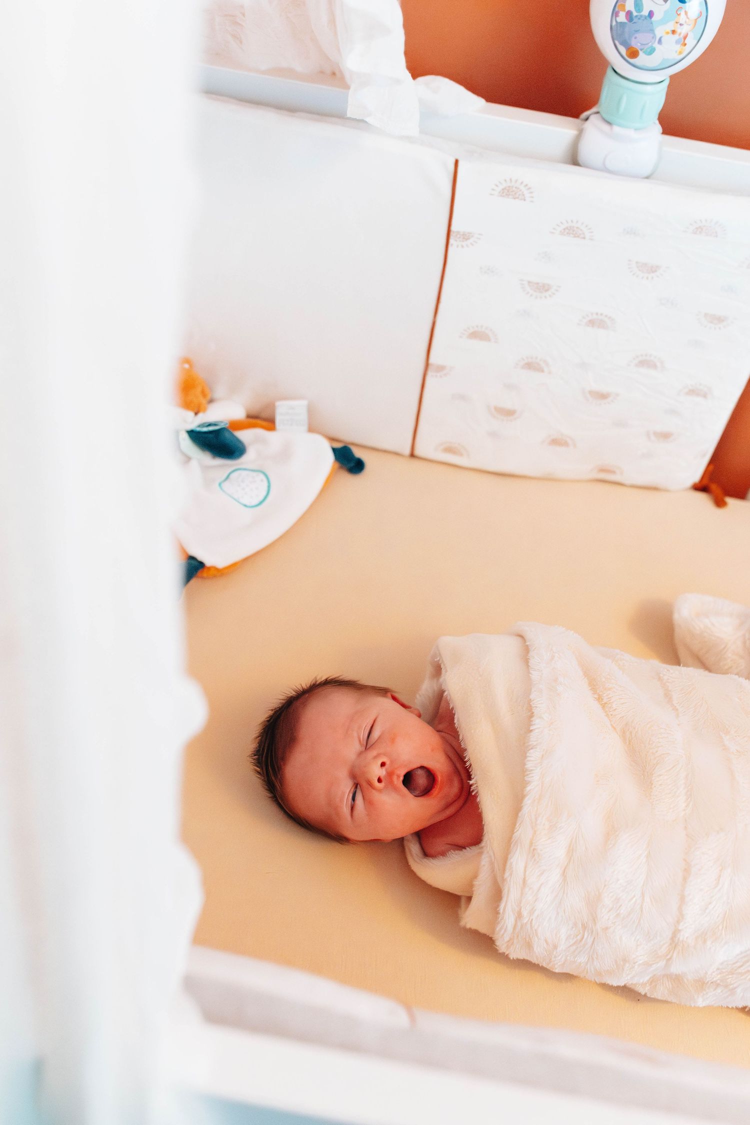 A swaddled baby lying in a hospital bassinet in various poses.