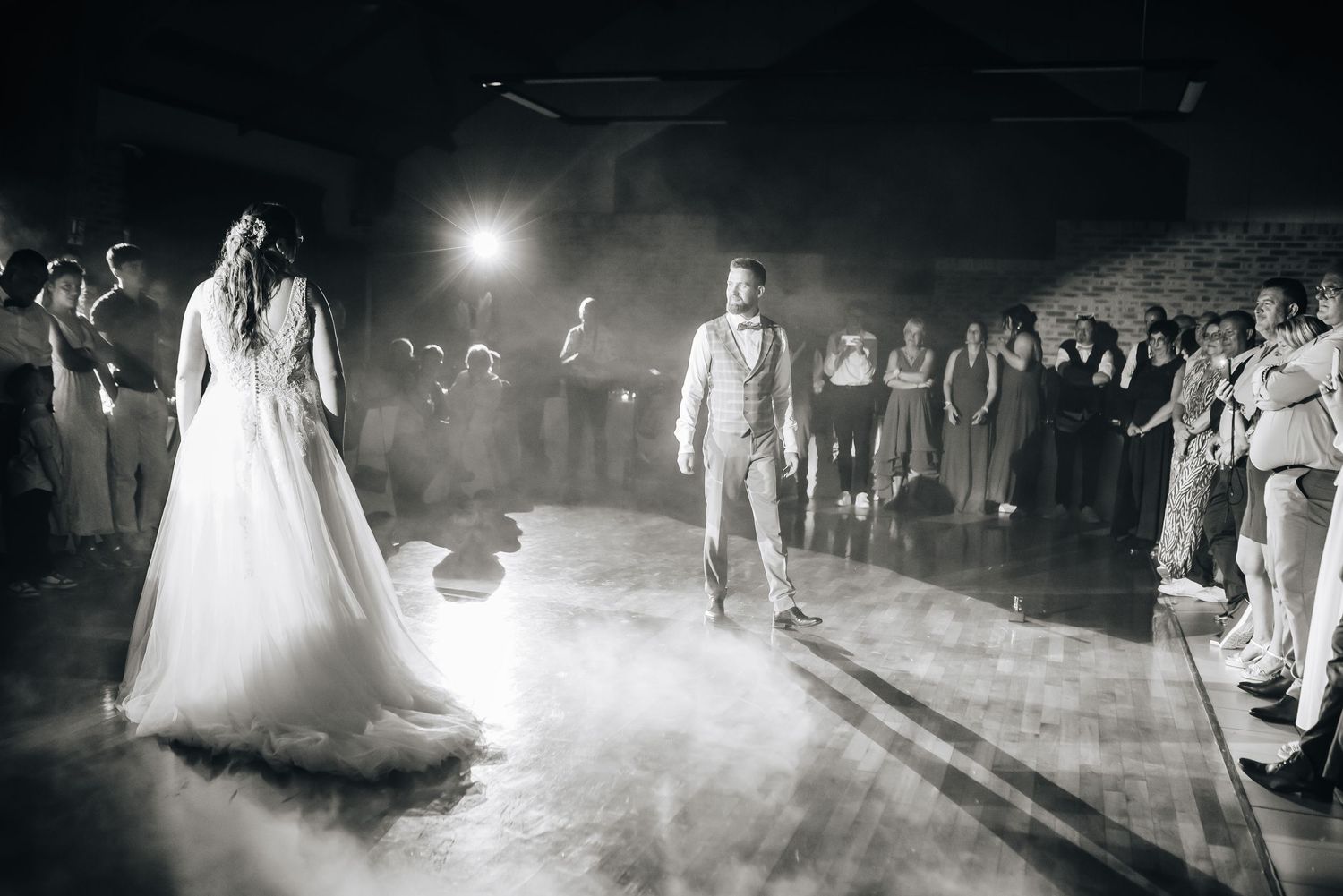 A dramatic first dance at a wedding reception with fog and spotlights creating an atmospheric scene on the dance floor.