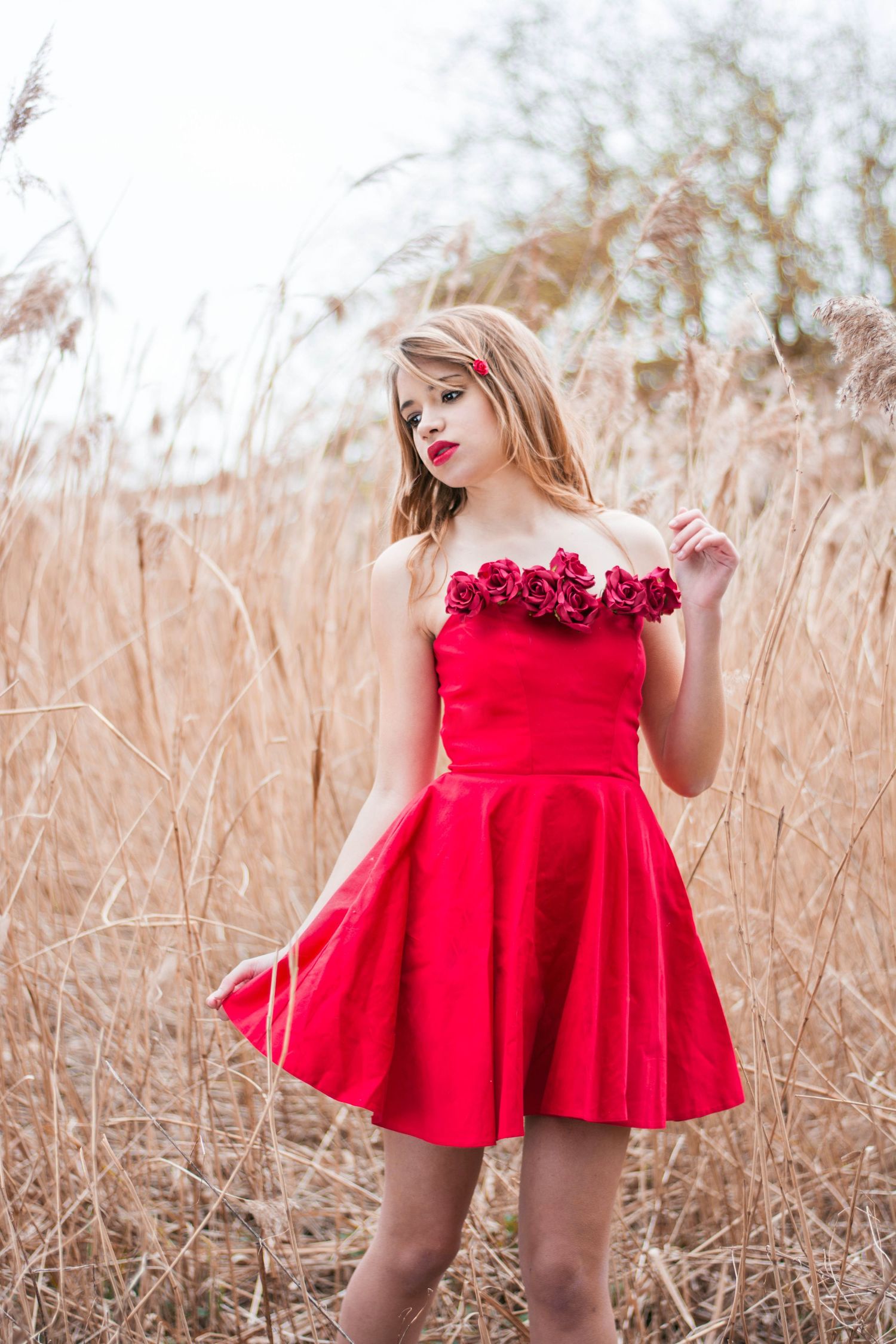 Red dress with floral details photographed in golden wheat field.