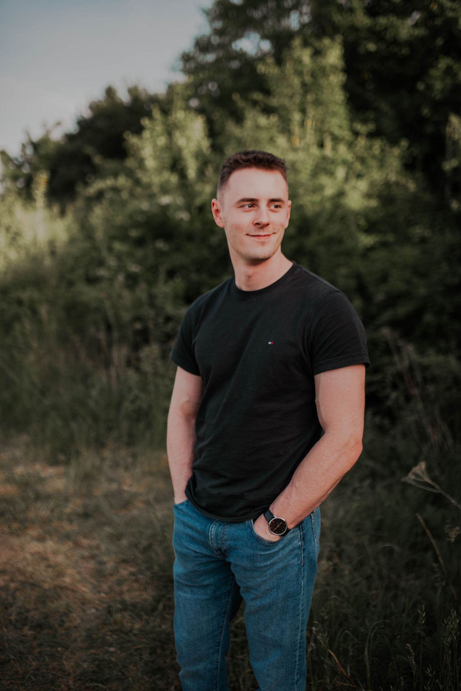Casual portrait series of person in black t-shirt and jeans against natural background.