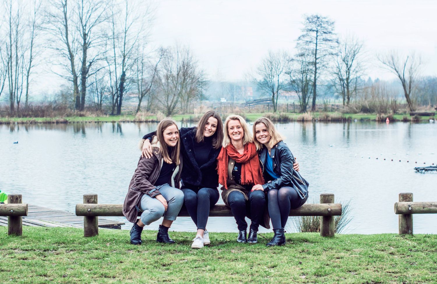 Group sitting together on wooden benches near a tranquil lake.