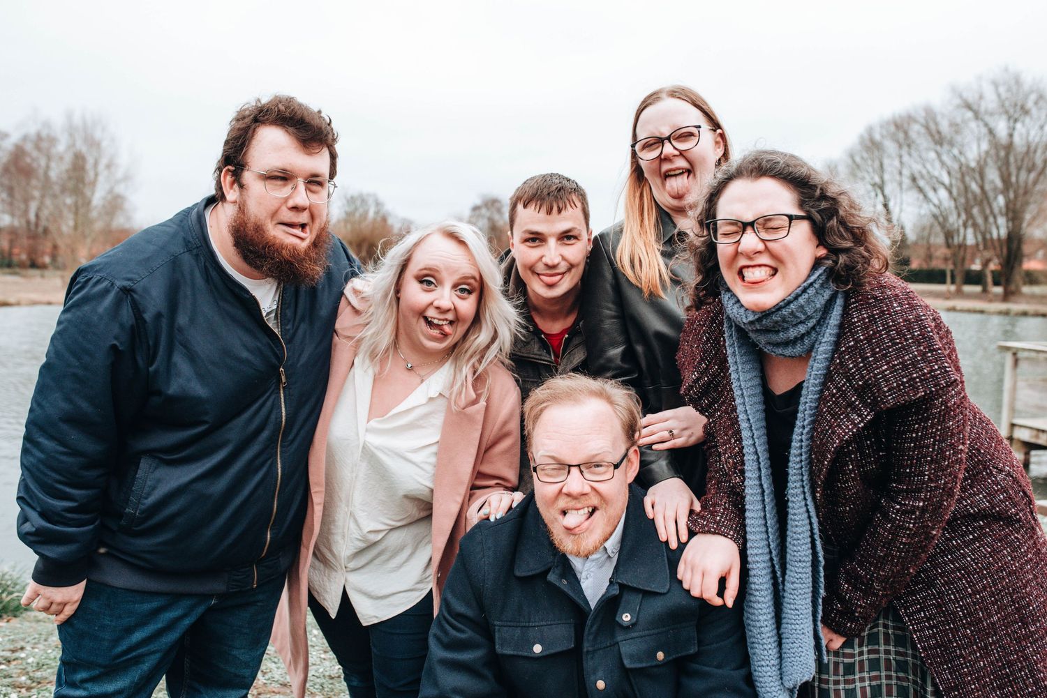 A group poses together outdoors on a cloudy winter day wearing casual attire.
