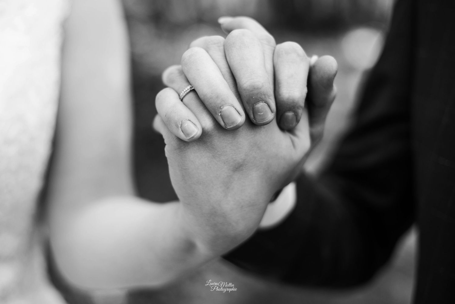Close-up of joined hands in an intimate black and white wedding photograph.