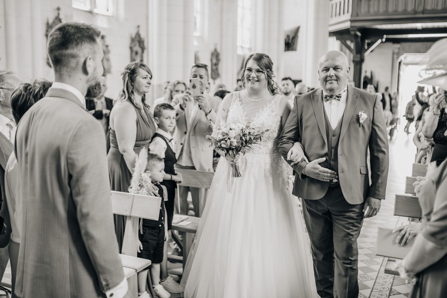 Black and white photo of wedding ceremony guests mingling in an elegant venue.