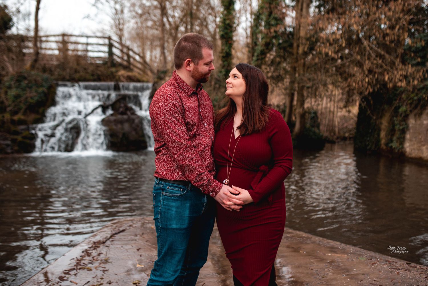 Romantic couple photos by a waterfall in autumn with rustic wooden bridge.