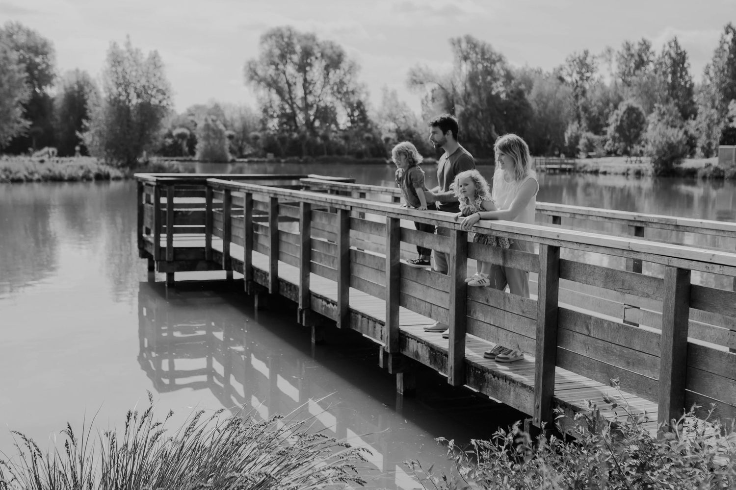 Scenic wooden boardwalk winding through a tranquil park with trees and water views.