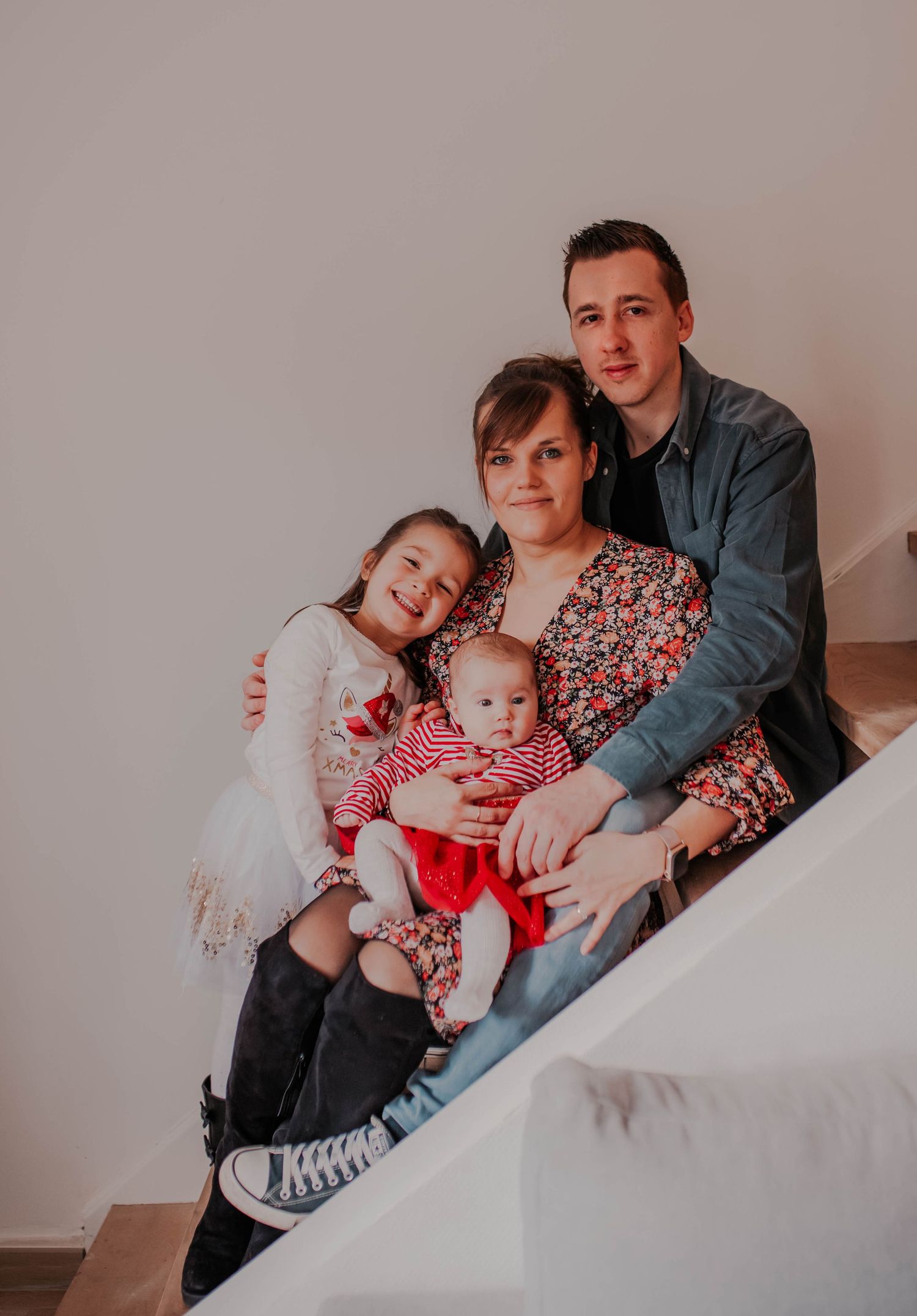 A family relaxing together on white stairs during an indoor photo session.