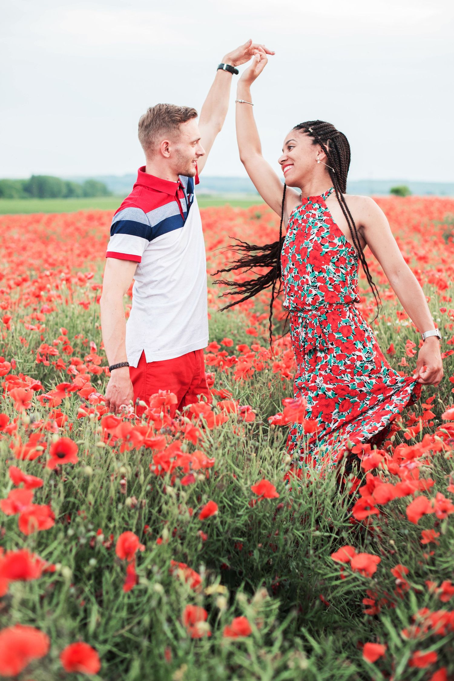 Dancing couple in red poppy field wearing coordinated red and white outfits.