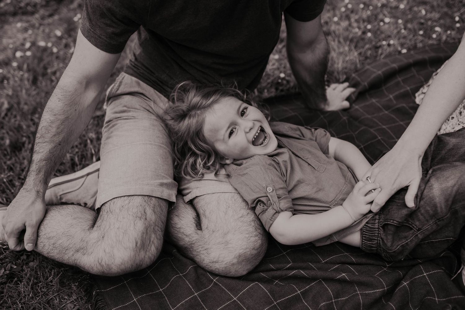 Black and white series of candid family moments captured on ground outdoors.