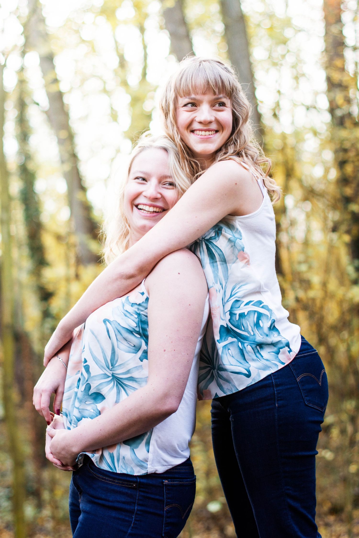 Playful outdoor photoshoot with two people in matching floral tops and dark pants.