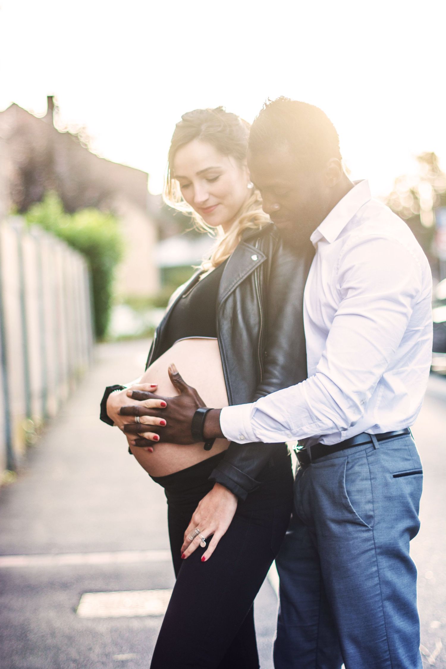 Sunset maternity photos of couple checking phones together outdoors.