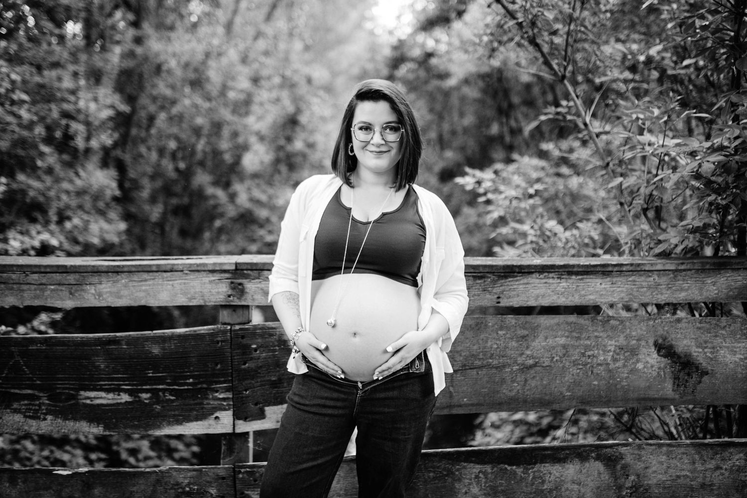 Black and white maternity photography session in outdoor park setting.