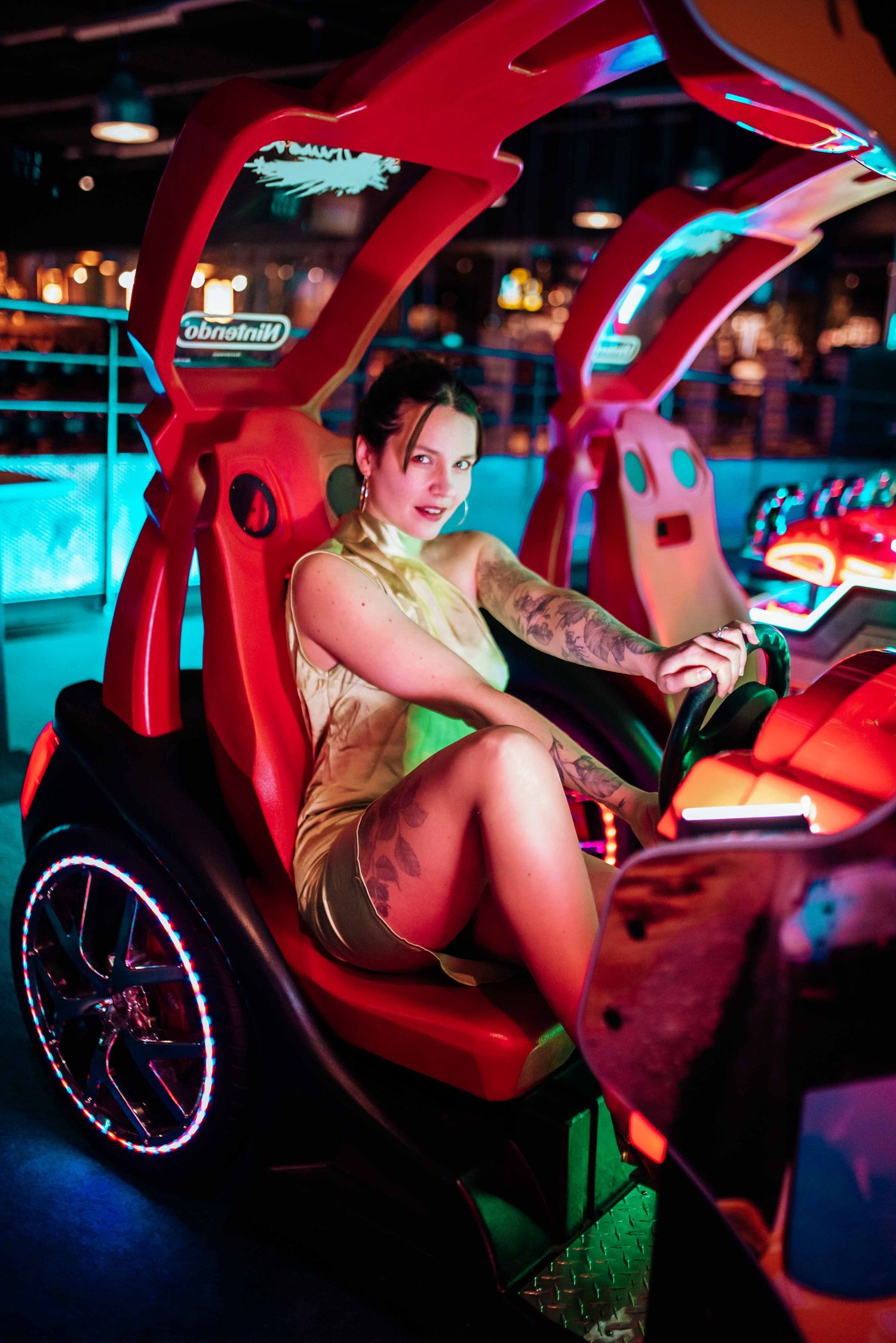 Neon-lit arcade photoshoot with retro gaming machines and dramatic red lighting.