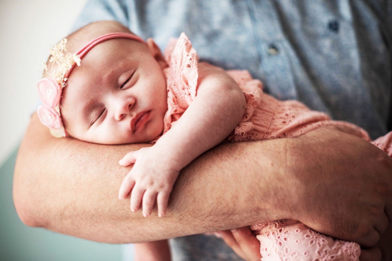 Sleeping newborn rests peacefully in pink swaddle during professional photoshoot.