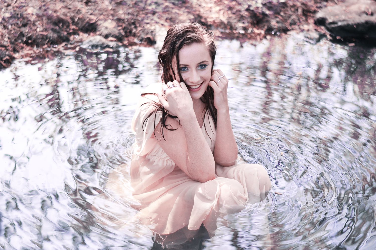 Person in light clothing creating ripples while submerged in reflective water.