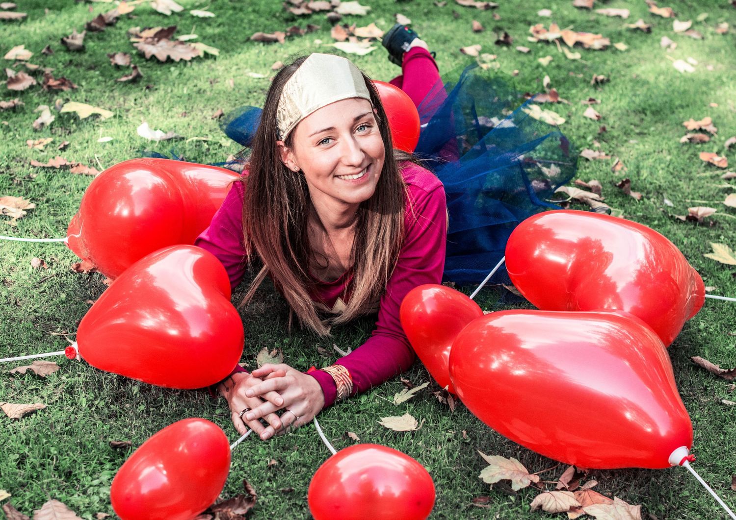 Red heart-shaped balloons scattered on grass in outdoor setting.